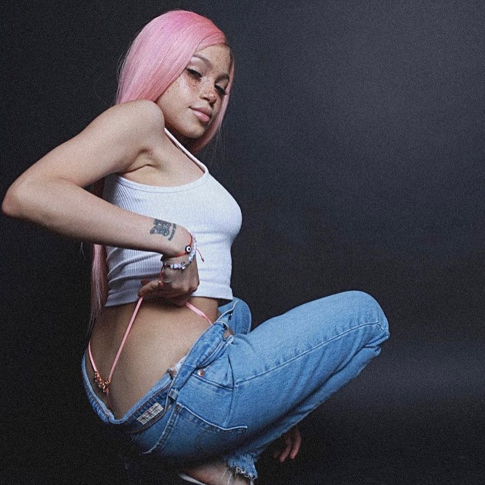 Woman modeling a pink custom-letter thong against a dark background